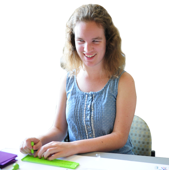 A teenage girls smiles as she uses a slate and stylus.